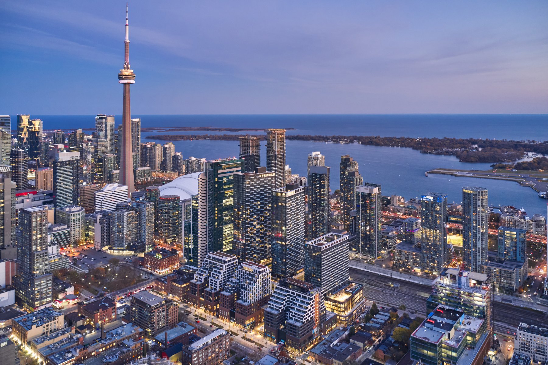Dusk aerial of The Well in Toronto, with the CN Tower and Lake Ontario